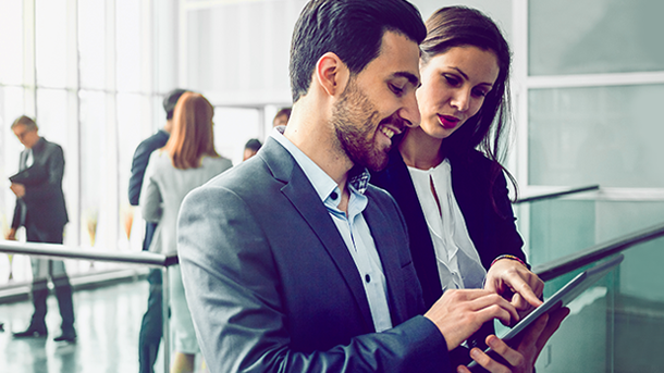 A business woman and man standing looking at a tablet